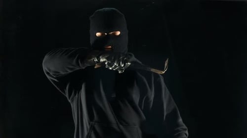 Masked Man Breaking Glass with Crowbar at Night