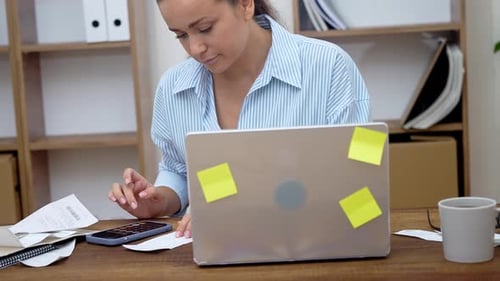 Female Accountant at Home Calculating Finances Using Calculator Managing Freelance Income Taxes