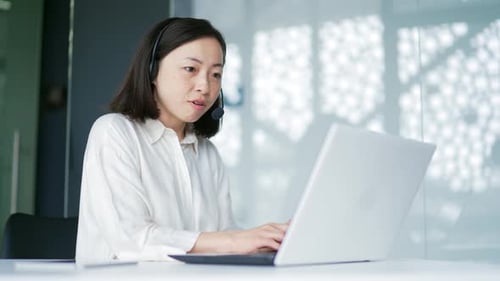 Woman With Headset Works on Laptop in Office