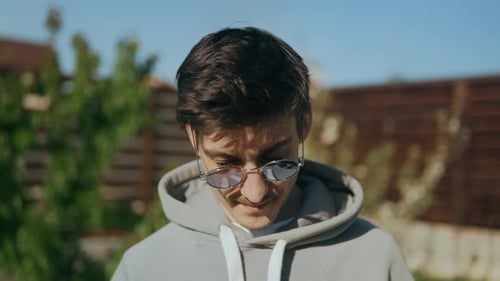 Young Adult Smiling in Sunglasses and Hoodie