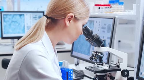 Woman Analyzing Sample with Microscope in Modern Laboratory