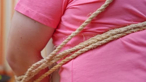 Kidnapped man desperately endeavors to loosen ropes binding