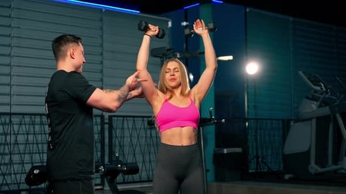 in the Gym Pair Training of a Guy Trainer and a Girl the Guy Controls the Work with Dumbbells