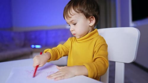 Ernstes süßes kaukasisches Kind, das sich auf das Zeichnen konzentrierte. Porträt eines schönen Jungen, der Spaß zu Hause hat.