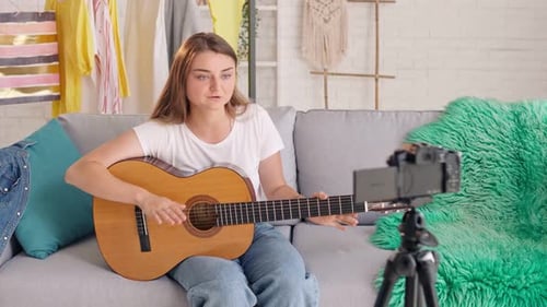 Woman Playing Guitar and Recording Video at Home
