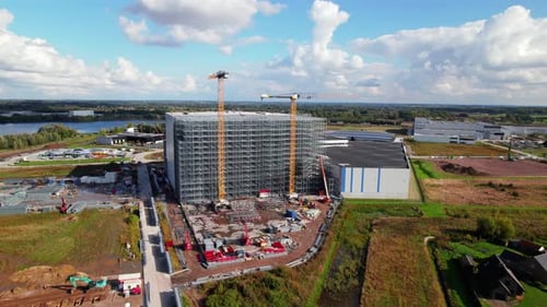 Disparo de un Zumbido que se mueve hacia una gran estructura que se está construyendo en un sitio de construcción con grúas