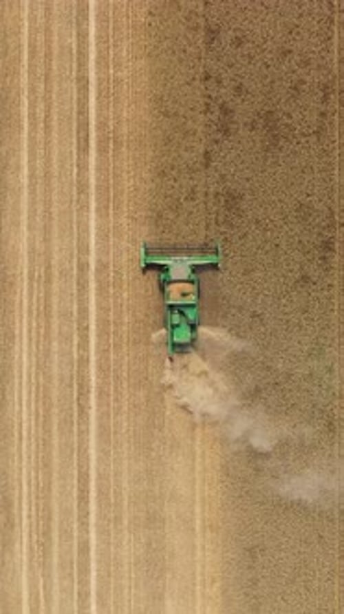 Aerial view of a combine harvester working in a field at summer