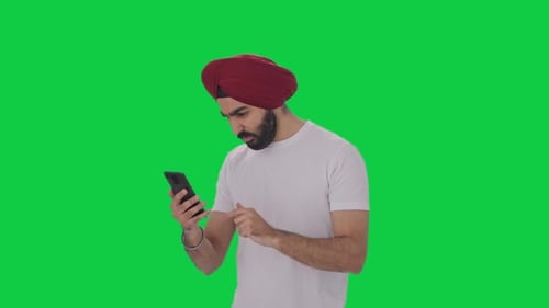 Sikh Indian man scrolling phone Green screen