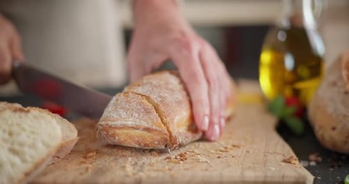 Slicing Crusty Bread on Cutting Board in Kitchen