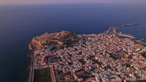 Aerial view of a coastal town with historical fortress at sunset