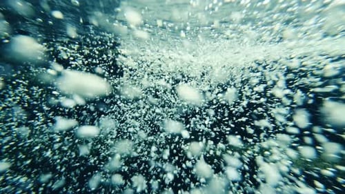 Bubbles rising underwater with rocks