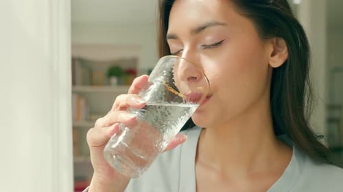 Adult caucasian woman drinks glass of pure water in the morning.