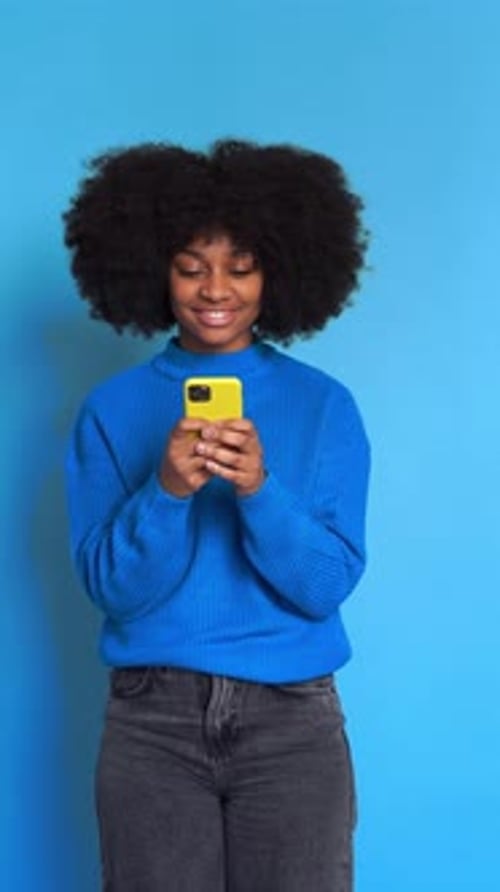Young Woman Using Smartphone on Blue Background