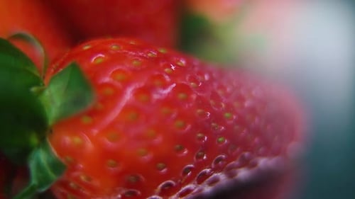 detailed video of a pile of strawberries, giant red RAW strawberry, green leaf, on a rotating stand,