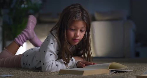 Portrait of Little Female Child Reading a Book in her Room Before Sleeping. Happy Cute Girl Readin