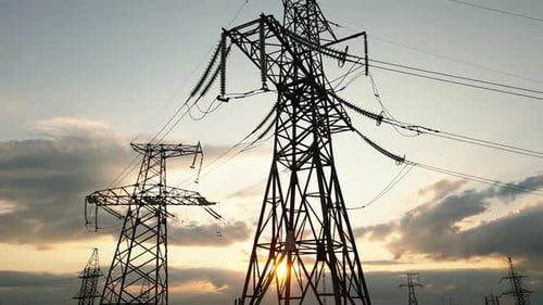 Electrical Towers Silhouetted Against Golden Sunset Sky