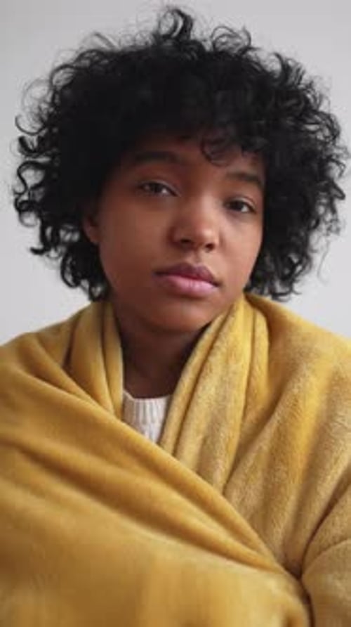 Adolescente afroamericano enfermo envuelto en una cálida manta en casa, vídeo vertical, retrato negro lindo
