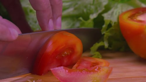 Close up of a chefs hands using a knife to slice a juicy tomato. SLOW MOTION