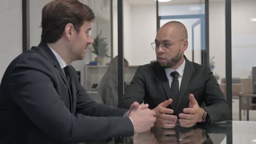 Two Men Talking at Glass Table in Office