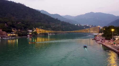 pont suspendu en fer illuminé par des feux de ferry avec vue sur les rives du Gange le soir, vue aérienne