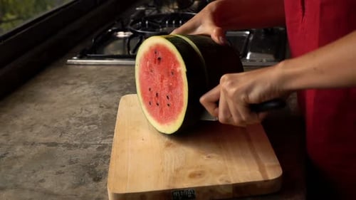 Female hands skillfully slicing fresh watermelon in a bright kitchen at home