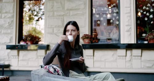 Young Woman Enjoying Coffee on Street