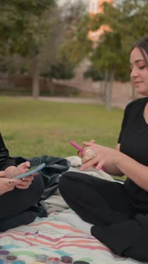 Young Women Sitting on Ground at Park Area Focusing on Smartphone Screen Slowmotion
