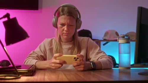 Woman Plays Game on Mobile Phone with Headphones
