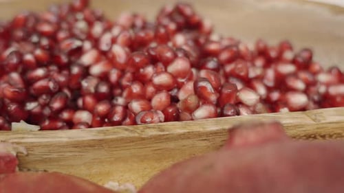 Rack focus of pomegranate seeds inside of wooden plate juicing and using fresh ingredients and fresh