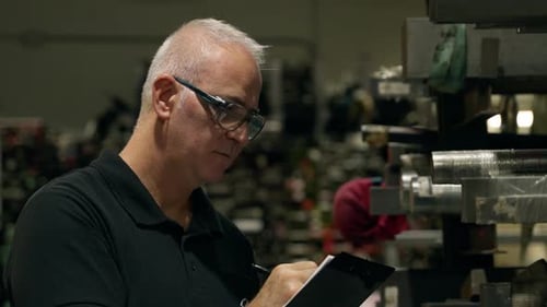 Supervisor Analyzing Production Line Taking Notes