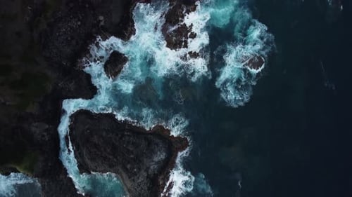 Aerial dolly shot, rocky coastline being invaded by crashing ocean waves