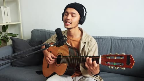 Young Man Playing Guitar and Singing at Home