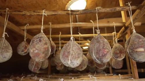 Cured Meats Hanging From Rafters in a Room