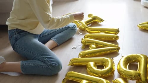 Young Adult Tying Balloons Together on Floor