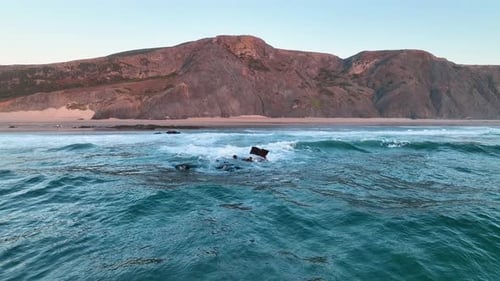 Cliff-lined beach with rolling surf waves