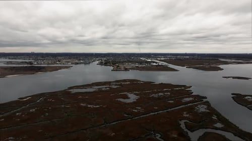 An aerial view over the salt marsh off Freeport, New York on a cloudy day. The drone camera dolly in