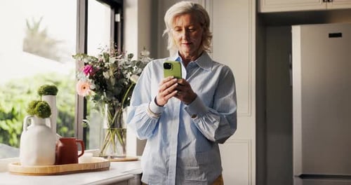 Woman uses smartphone in bright modern kitchen