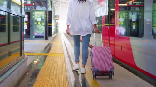 Female Passenger with Rolling Suitcase Walking Along the Station Platform