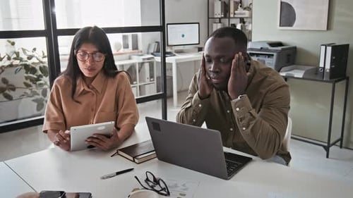 Exhausted Employee Working on Laptop in Office
