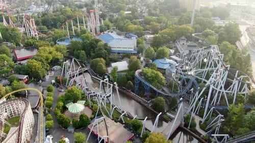 Slow dolly forward drone shot revealing a maze of roller coasters and rides at amusement park