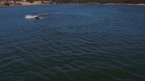 Luftdrohne eines Mannes, der auf einem eigenen Wasserfahrzeug auf einem See fährt