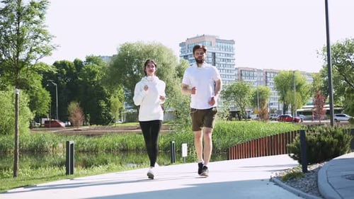 Couple of Young Caucasian People Starting Morning Run Along City Street Cheerful Woman and Bearded
