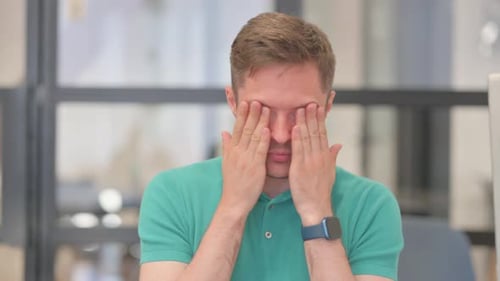 Man Experiencing Headache Rubbing Temples in Office