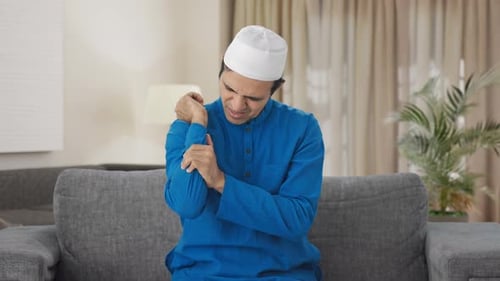 Man Massaging Sore Arm and Wrist Indoors