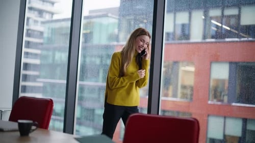 Smiling Woman Talking on Smartphone in Rainy Office