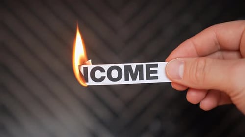 Burning “INCOME” concept symbolizing job loss, reduced earnings, financial hardship, cash flow