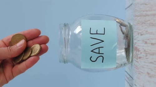 Hand Saving Money in Glass Jar, Portrait Orientation