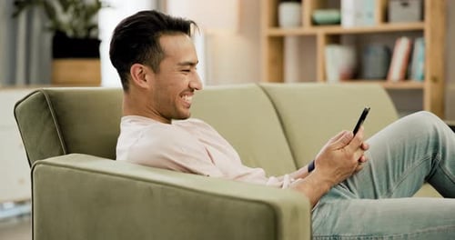 Man Relaxing on Couch Using Smartphone at Home