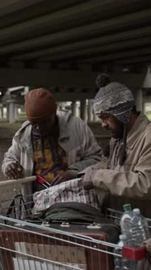 Two men sort through items in shopping cart
