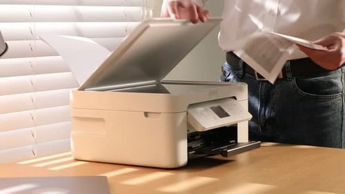 Hombre trabajando con la impresora en un escritorio de madera en el interior, de cerca